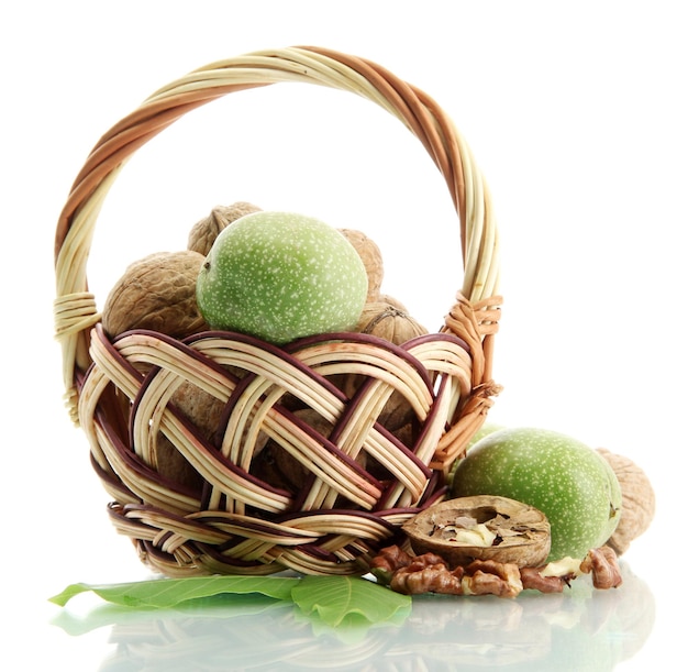Walnuts with green leaves in basket isolated on white
