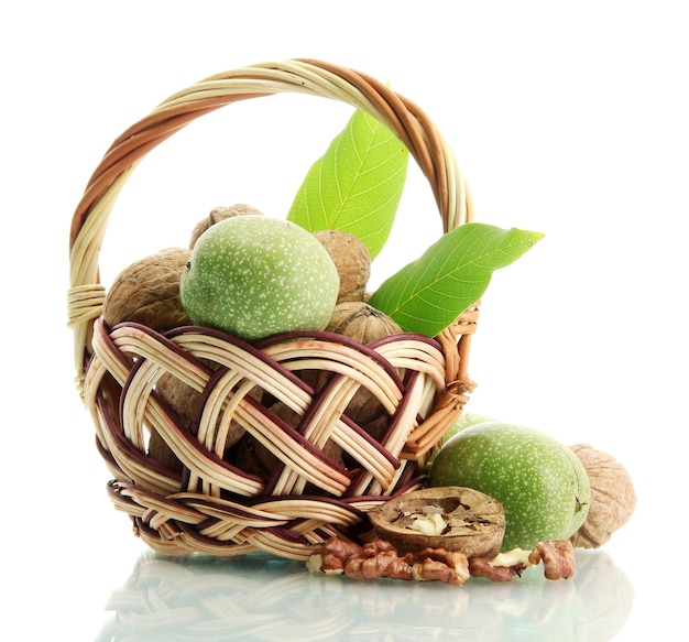 Walnuts with green leaves in basket, isolated on white