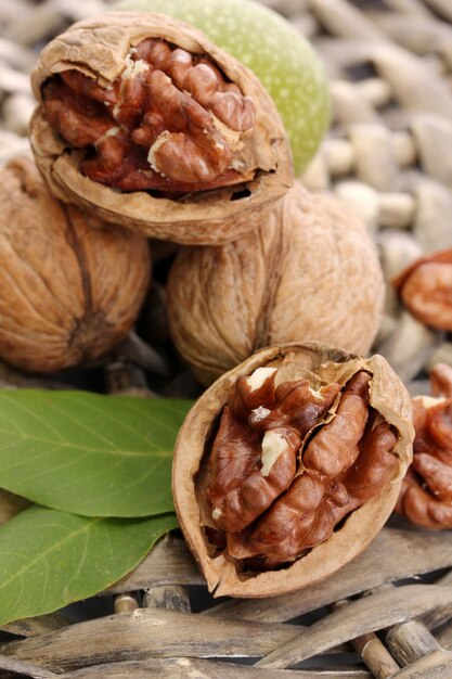 Walnuts with green leaves on wicker background