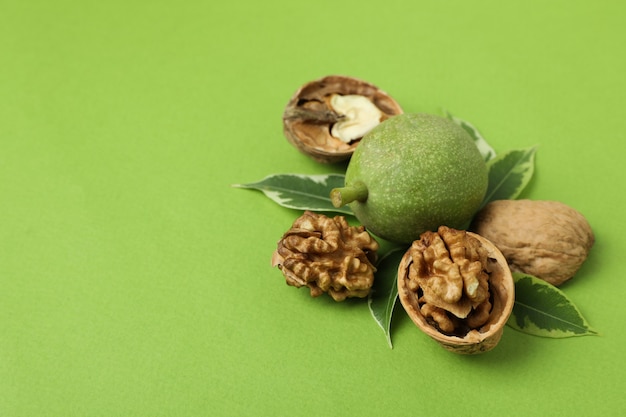 Walnuts with nut peel on green background