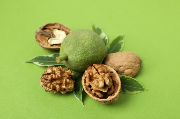 Walnuts with nut peel on green background