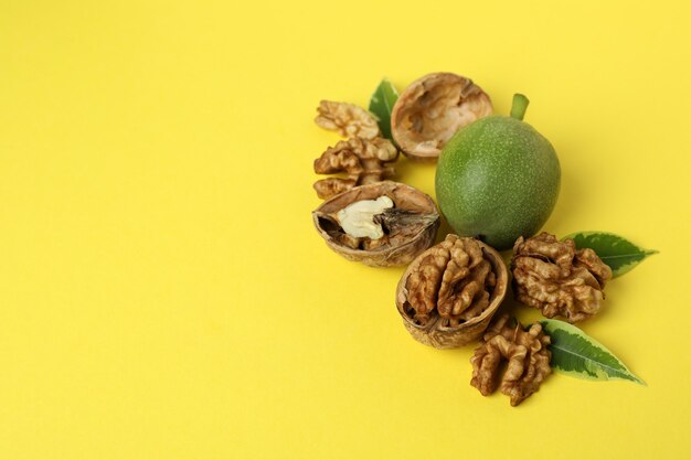 Walnuts with nut peel on yellow background