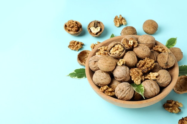 Walnuts in wooden bowl on blue background