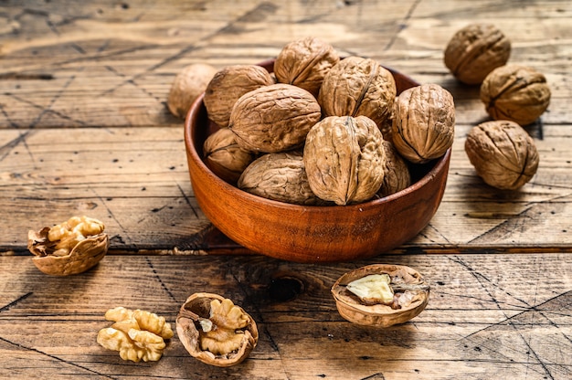 Walnuts in a wooden plate and walnut kernels.