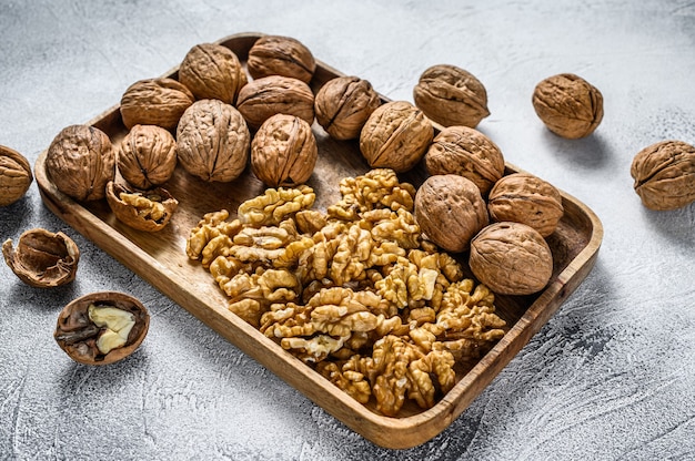 Walnuts in a wooden plate and walnut kernels.