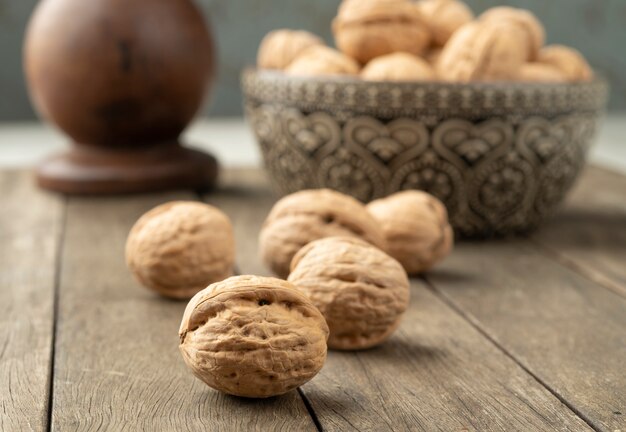 Walnuts over a wooden table and into a bowl.