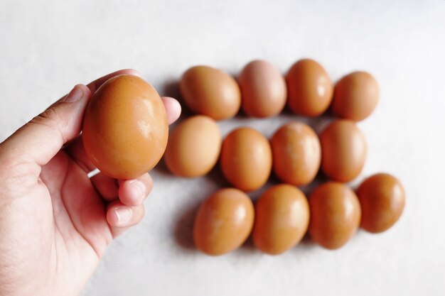 Waman Hand holding Fresh chicken eggs on white concrete floor background. The benefits of eating eggs are high protein.