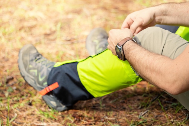 Wandelaar draagt beenkappen over trekkingschoenen om te beschermen tegen waterinsecten en kou Kleding en uitrusting voor backpacken en kamperen