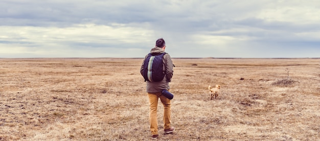 Wandelaar en hond wandelen in grasland