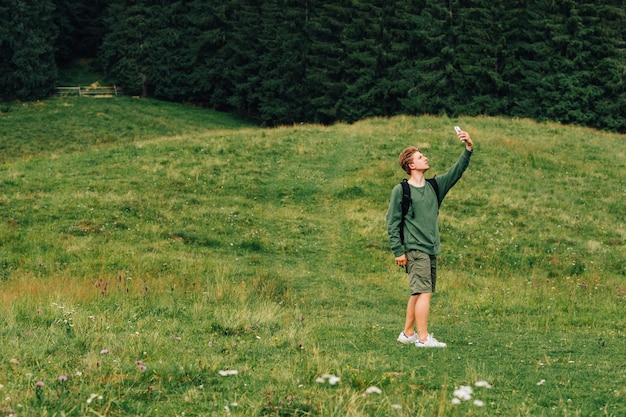 Wandelaar jonge man met rugzak fotograferen van het prachtige landschap van de berg in de zomer