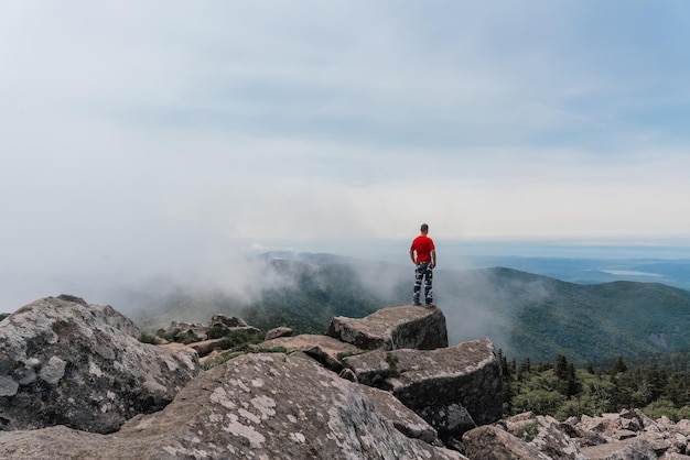 Wandelaar man op de top van de berg geniet van de luchtfoto terwijl hij zijn handen opsteekt boven de wolken Mount Pidan