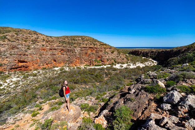 wandelaar meisje met rugzak staat op de top van de berg met uitzicht op de kloof in Cape Range National Park