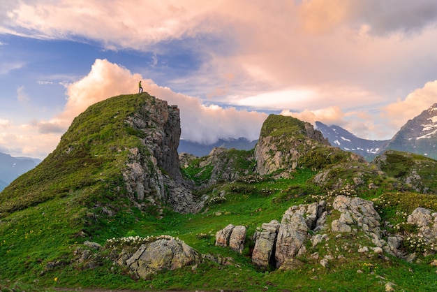 Wandelaar met een rugzak op een groene bergtop tegen de achtergrond van de avondrood