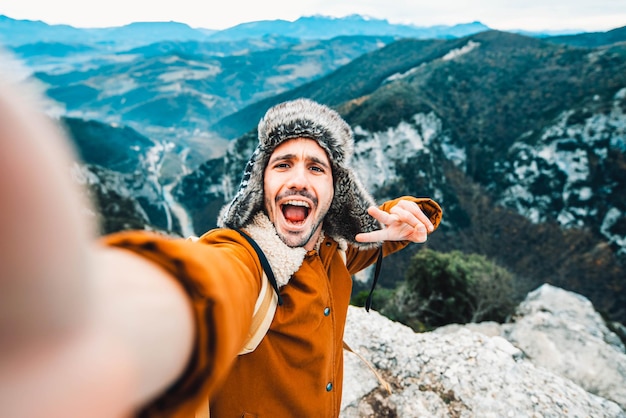 Foto wandelaar met rugzak die selfie op de top van de berg neemt