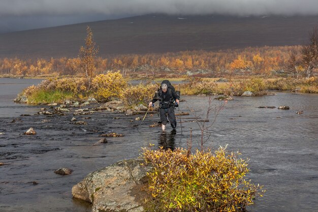 Wandelaar met rugzak steekt koude kreek over. tijdens een trektocht in Sarek