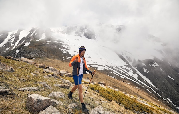 Foto wandelaar met wandelstokken in de mistige bergen