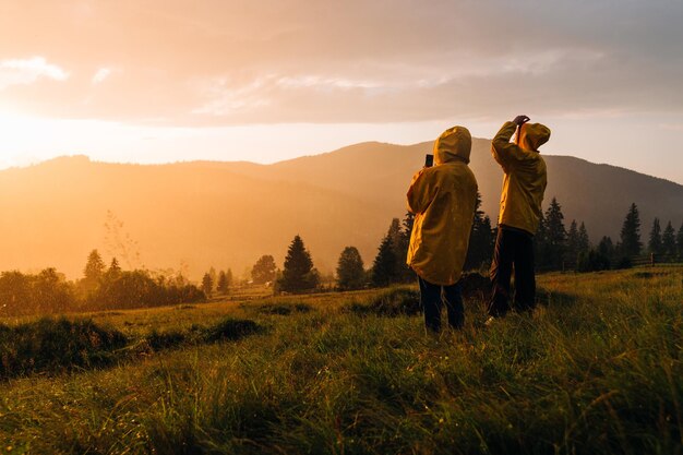 Wandelaars in de regen bij zonsondergang kijken naar het prachtige landschap