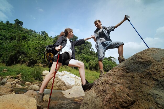 Wandelaars lopen langs een parcours op een berg met wandelstokken Avontuurlijke reizen toerisme wandeling en mensen concept Groep lachende vrienden met rugzakken buitenshuis