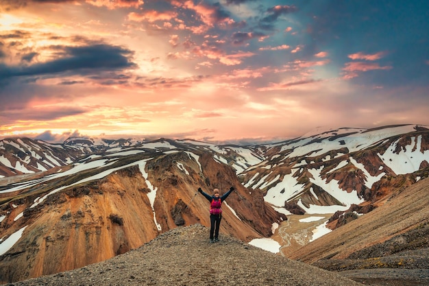 Wandelaarvrouw die op de top staat met een vulkanische bergketen met sneeuw bedekt op Blanhjukur-pad in Landmannalaugar