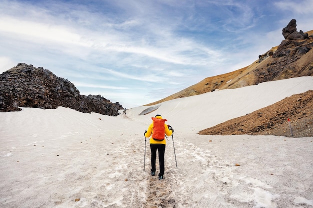 Wandelaarvrouw met reisexpeditie op besneeuwde berg in hooglanden van ijsland bij landmannalaugar-trail