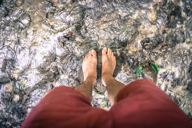 Wandelen buiten in het bos Gesneden uit mannelijke blote voeten in een ondiep zoet rivierwater