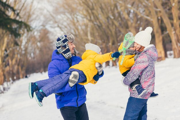 Wandelen in winter park samen, twee volwassen man en vrouw en twee kinderen en gelukkige familie