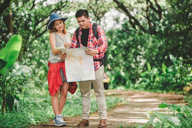 Wandelen - wandelaars kijken naar kaart. Paar of vrienden navigeren samen lachen gelukkig tijdens camping reizen wandelen buitenshuis in het bos. Jonge gemengd ras Aziatische vrouw en man.