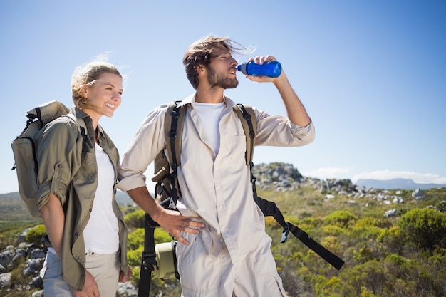 Wandelend paar dat zich op bergterrein bevindt dat een onderbreking neemt