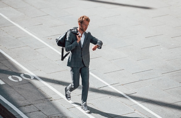 Wandelingen op de weg Jonge zakenman in grijze formele kleding is buiten in de stad