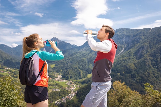 Wandelpaar wandelen op een heuvel in de natuur in de zomer en drinkwater