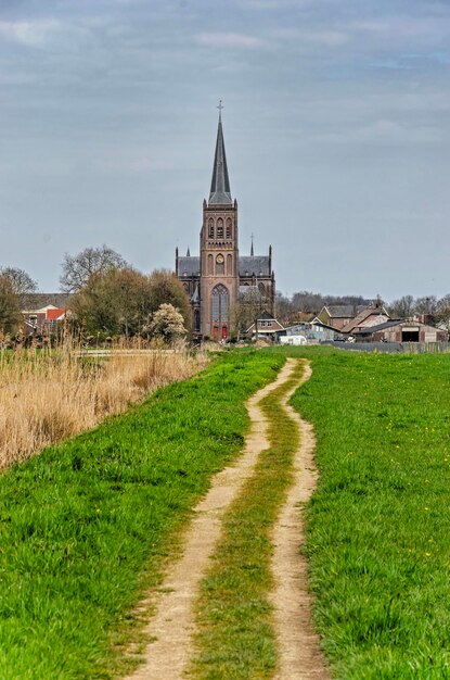 Foto wandelpad door de weiden dat rechtstreeks naar de dorpskerk leidt