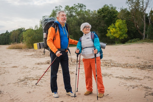 Wandeltoerisme avontuur ouderenpaar man vrouw genieten van buitenrecreatie wandelen op het strand gelukkig