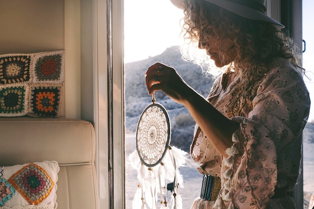 Wanderlust lifestyle mensen Een vrouw met dreamcather decoratie op de deur van haar stacaravan met buitenshuis en zonsondergang tijd buiten Concept van het leven en vrijheid Gelukkig leven onafhankelijke vrouw