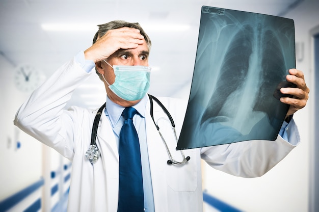 Wanhopige gemaskerde dokter kijkt naar een radiografie