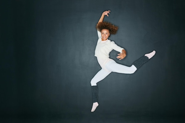 Wanneer je danst, beweeg je Wanneer je beweegt, leef je Studio-opname van een aantrekkelijke jonge vrouw die danst tegen een grijze achtergrond