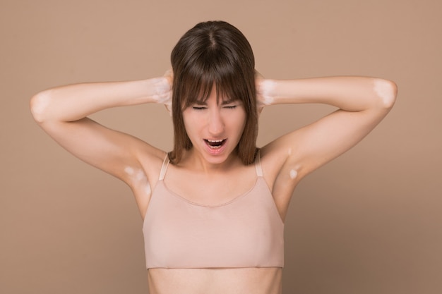 Do not want to hear. A long-haired young woman with skin pigmentation closing her ears