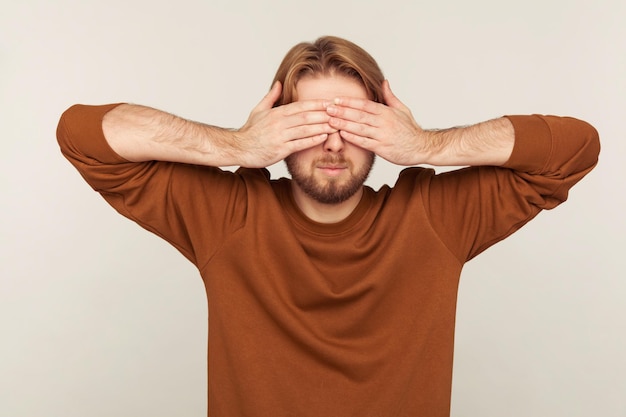 Don't want to look at this. portrait of bearded man covering
eyes, feeling stressed afraid, refusing to watch