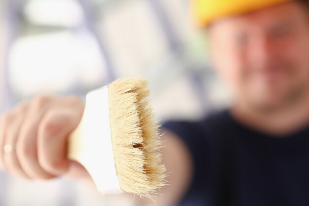 Foto wapen van het glimlachen van de borstelclose-up van de arbeidersholding