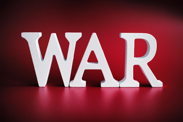 WAR word written in wooden alphabet letters on red background The concept of a terrible war destroying country