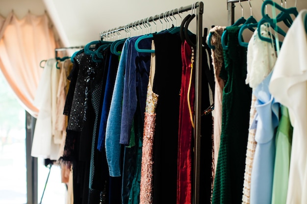 Wardrobe hangers with colorful dresses in the room