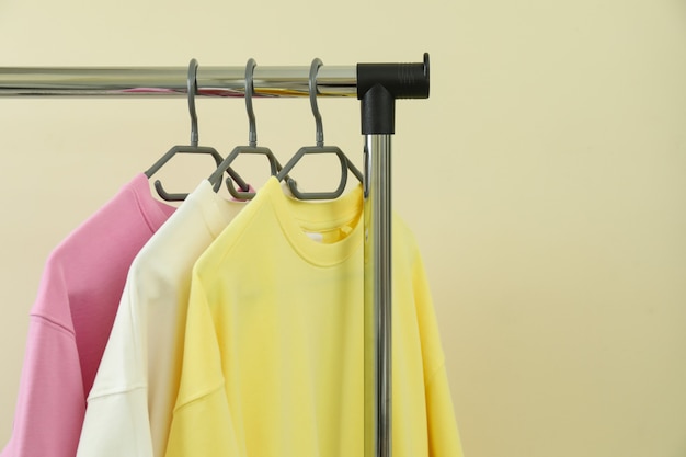 Wardrobe rack with sweatshirts against beige surface