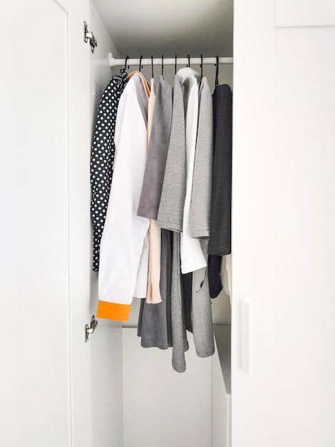 Wardrobe with basic clothes in room scandi interior