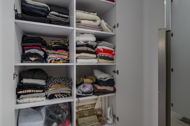 Photo wardrobe with different clothes at shelves