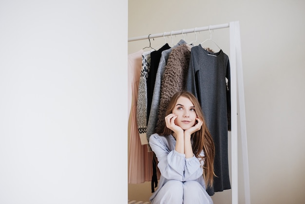 Photo wardrobe of a young girl. dresses on hangers. flour choice. what to wear? a girl in pajamas does not know what to wear.