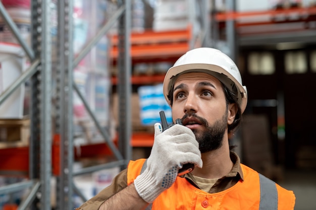 Warehouse engineer using walkie-talkie while looking upwards