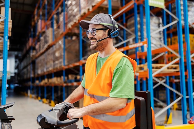 A warehouse man is driving forklift in facility and working with goods and shipment