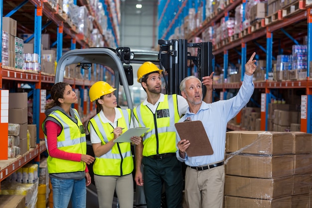 Warehouse manager and co-workers discussing over clipboard