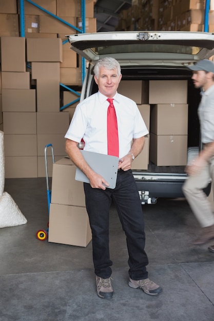 Warehouse manager smiling at camera with delivery in background