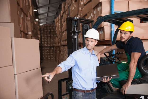 Warehouse manager talking with forklift driver