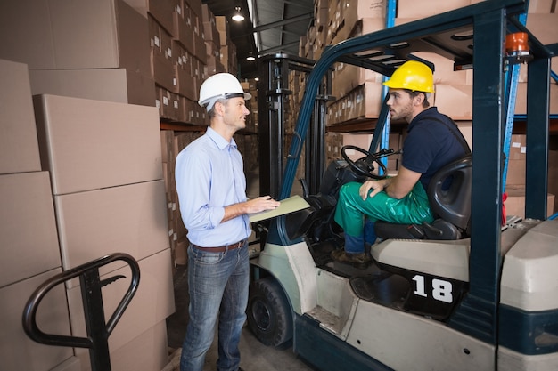 Warehouse manager talking with forklift driver